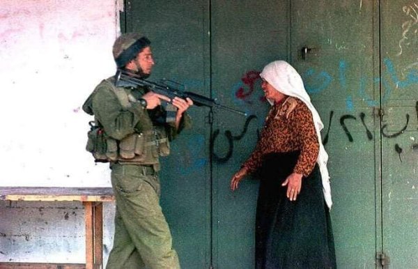 سيدة فلسطينية تتصدى لأحد جنود الاحتلال وتحاول منعه من إطلاق النار على أطفال الانتفاضة الأولى في مخيم جباليا شمال قطاع غزة - مارس 1991